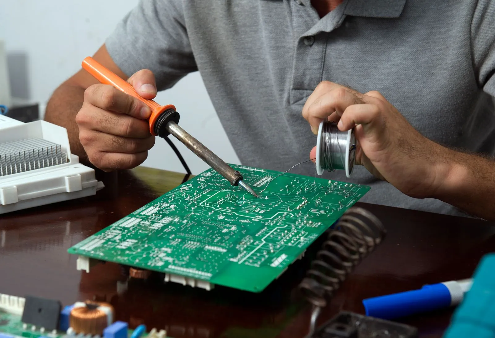 Hands soldering a circuit board at a workbench